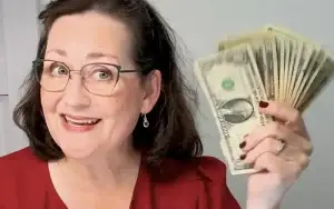 woman sitting at sewing machine and holding up money