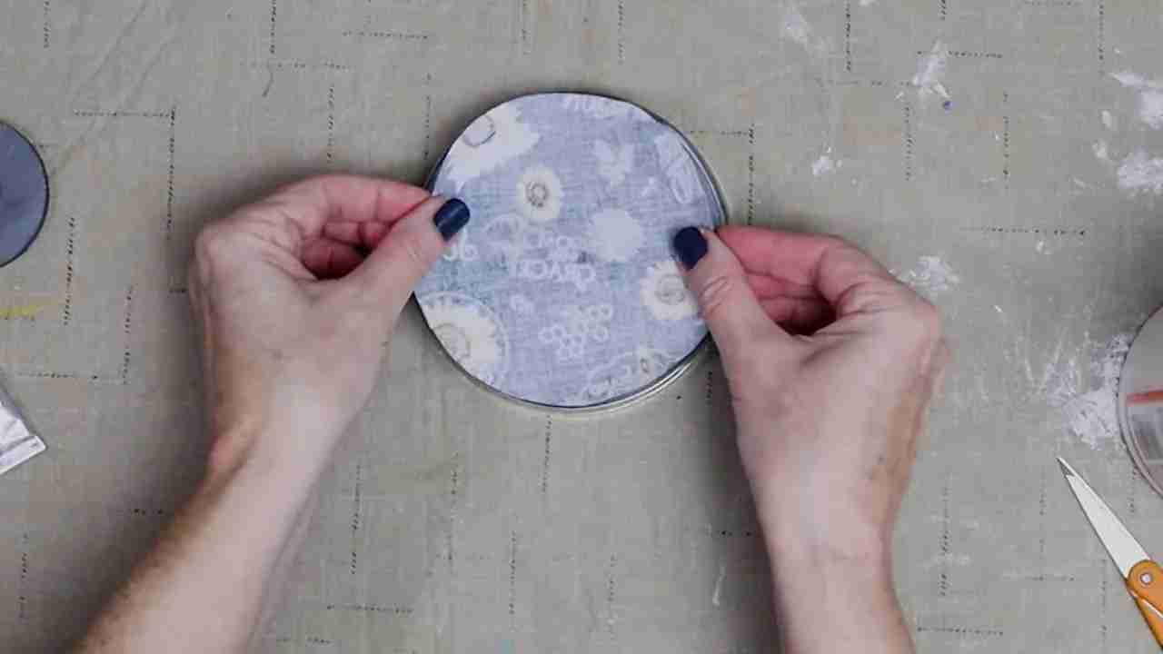 Hands positioning a fabric circle wrong side up on the underside of a glass plate